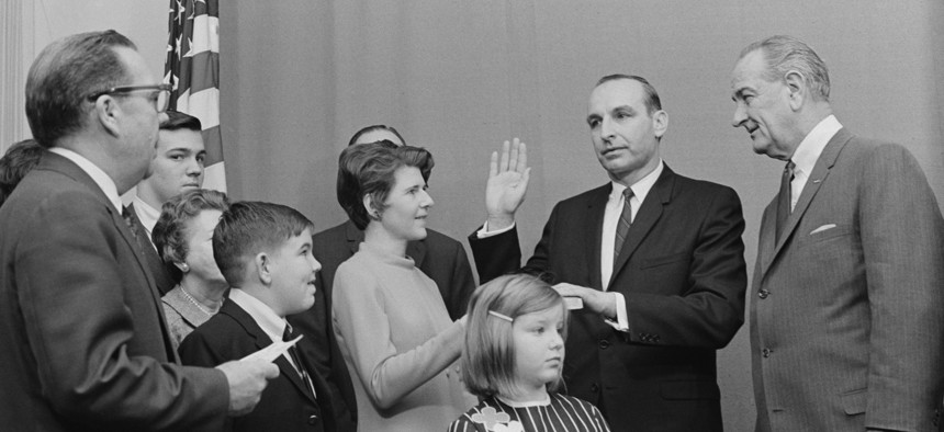 Charles Zwick, shown here taking his oath of office alongside President Lyndon B. Johnson and his family, led the Office of Management and Budget when Circular No. A-97 was adopted.