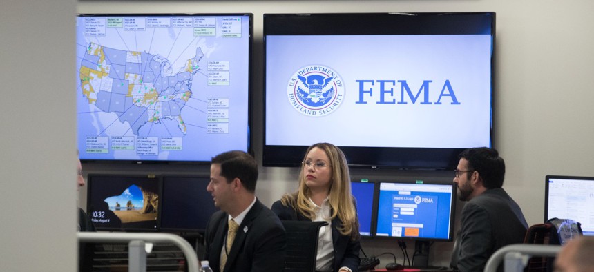 Employees sit in front of computer monitors at the command center of the Federal Emergency Management Agency.